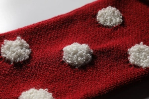 Macro de tissu de Noël tricoté rouge avec texture de pois en peluche blanche 3D