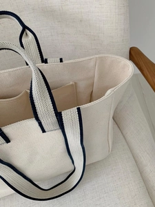 Detailed close-up showing two inner pockets and durable beige canvas material of the tote bag