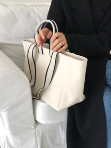 Close-up of cream canvas tote bag with contrast navy blue webbing handles and trim