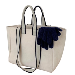 Beige canvas tote bag with navy blue trim handles and matching knitted gloves inside