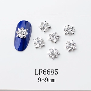 Détail macro d'un bijou d'ongle fleur 9x9mm avec strass sur un ongle bleu