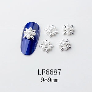Détail macro de charmes d'ongles fleurs argentées 9x9mm avec perles sur manucure