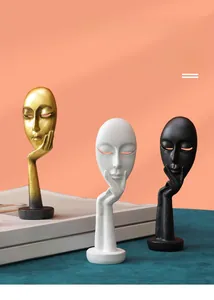 Close-up of minimalist resin face art ornaments in gold, white, and black finishes