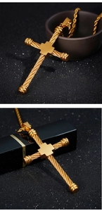 Detailed view of gold cross pendant with twisted rope texture on a black background