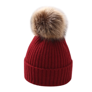 Winter red knitted baby hat with a large brown faux fur pom pom for boys and girls