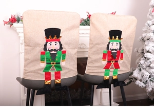 Detail of nutcracker soldier burlap chair covers set against a festive fireplace background
