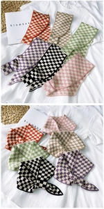 Close-up of soft knitted plaid scarves in various colors on a white bedding background