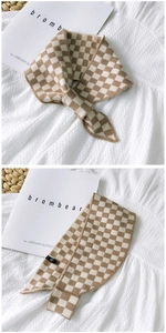 Detail of beige and white checkered knit neckerchief scarf on a flat lay display