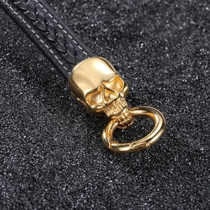 Braided leather skull bracelet in black and gold stainless steel shown on stone background
