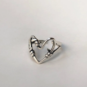 Close-up of minimalist 925 sterling silver knotted heart-shaped open ring detail
