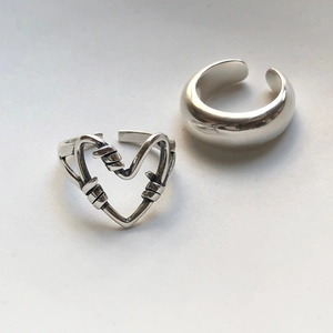 Close-up of S925 silver knotted heart ring and thick open band with barbed wire detail