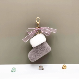 Detail of plush Christmas boot keychain with purple bow and gold metal clasp
