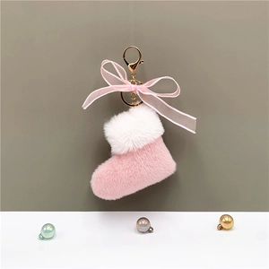 Close-up of plush pink Christmas boot keychain with white faux fur and a golden clasp