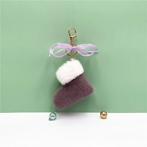 Close-up of purple plush Christmas boot keychain with organza bow and golden clasp