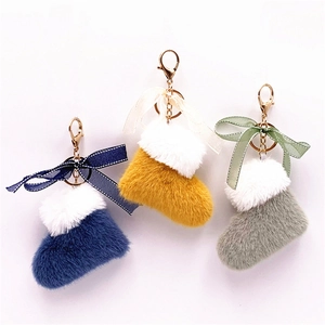 Three plush Christmas boot keychains with faux fur trim and bows in blue, yellow and grey