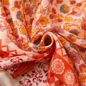 Macro view of vintage floral cotton linen scarf with orange print and red fringe detail