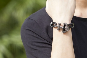 Close-up of a men's black braided leather bracelet with a silver anchor axe charm