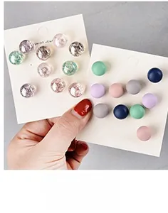 Detail showing various colors of round stud earrings with stone texture and matte finishes