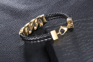 Detail of black woven leather bracelet with golden steel chain on alligator box