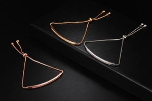 Detail of adjustable zircon bar bracelets in gold, silver, and rose gold on a black box