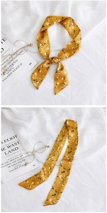 Detail of yellow floral skinny silk scarf styled on book with vintage aesthetic
