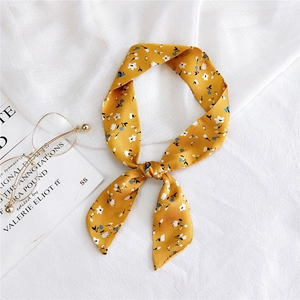 Elegant yellow floral skinny scarf tied as a bow on silk fabric with stylish glasses