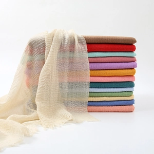 Detailed view of stacked candy-colored crinkled scarves with soft fringe texture design.