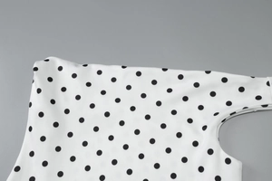 Detailed view of white polka dot fabric with high-quality stitching and breathable texture