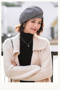 Close-up of black and white houndstooth beret hat paired with cozy knit cardigan