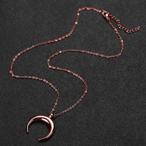 Minimalist stainless steel crescent moon pendant necklace in rose gold on black background