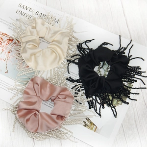Detailed view of satin hair scrunchies with faux pearl fringe in three elegant colors