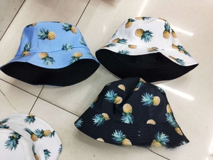 Detailed flat lay of cotton bucket hats in blue, white, and black with pineapple prints