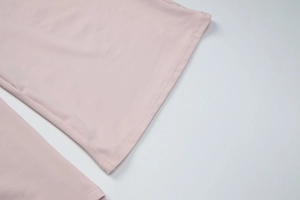 Detail of light pink elastic knit fabric showing high-quality double-needle flat stitching