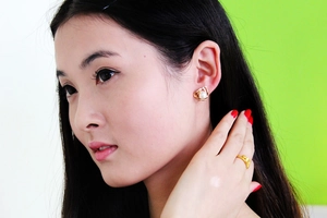 Detail of elegant triangle pearl stud earring worn with gold wrapped silk design