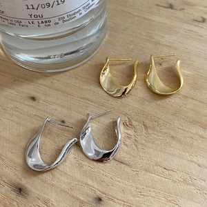 Macro view of gold and silver U-shaped polished sterling silver earrings on wood