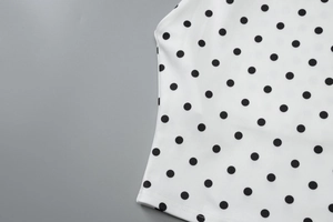 Detailed view of the white fabric with classic black polka dots and smooth texture