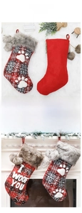 Detail von Weihnachtsstrümpfen in Pfotenform mit Karomuster und Plüschbommeln am Kamin aufgehängt