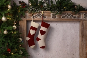Close-up of red and white knitted Christmas stockings with 3D heart patterns by the fireplace