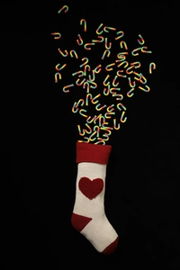 Close-up of white knitted Christmas stocking with red heart and candy canes inside