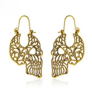 Detailed close-up of vintage gold filigree skull earrings with gothic bohemian patterns