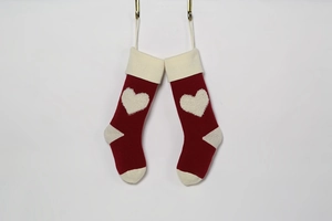 Detailed view of red knitted Christmas stockings with 3D heart pattern and cream accents