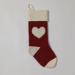 Detail of red knitted Christmas stocking featuring a white plush 3D heart and hanging loop