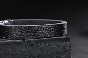 Gros plan du bracelet en cuir noir motif litchi avec fermoir magnétique en argent