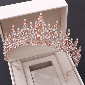 Gros plan d'une couronne de mariée or rose avec cristaux champagne dans un coffret