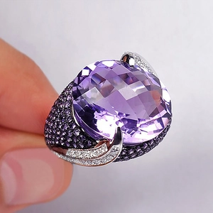 Classic silver cocktail ring featuring a large oval purple zircon and pavé side stones