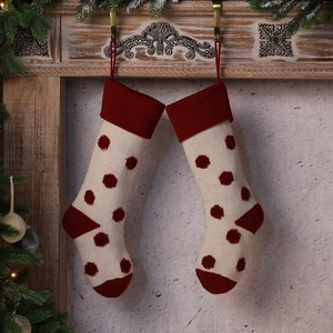 Chaussettes de Noël en tricot à pois rouges suspendues sur une cheminée décorée