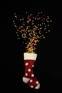 Vue dynamique de bonbons colorés sortant d'une chaussette de Noël tricotée à pois rouges 3D