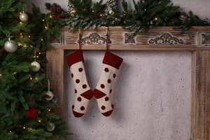 Détail de chaussettes de Noël en tricot à pois rouges suspendues à une cheminée en bois