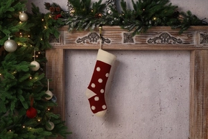 Détail d'une chaussette de Noël en tricot rouge à pois blancs dans un décor festif