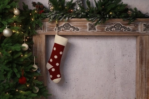 Chaussette de Noël en tricot rouge foncé à pois blancs suspendue à une cheminée festive